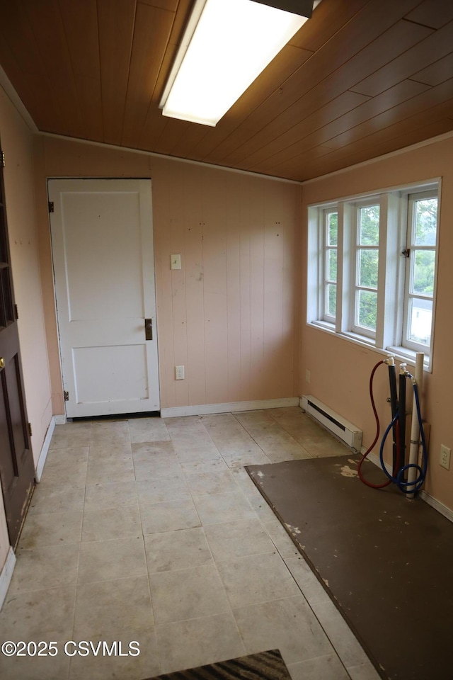 empty room with a baseboard heating unit, wood ceiling, and baseboards