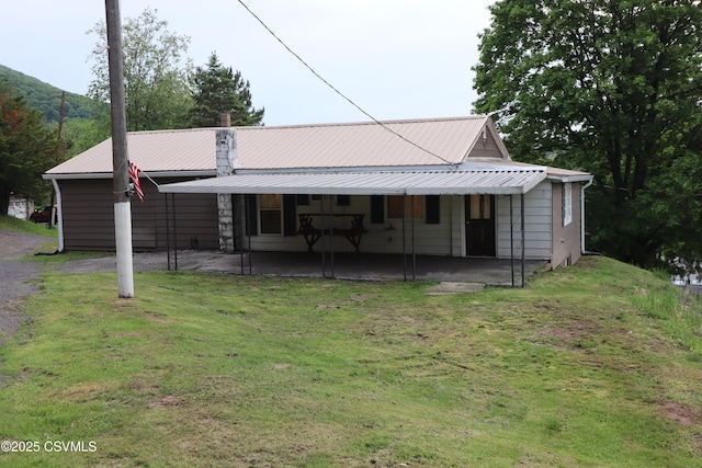 back of property featuring a lawn, a patio area, and metal roof