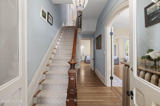 entrance foyer featuring arched walkways, wood finished floors, and stairs