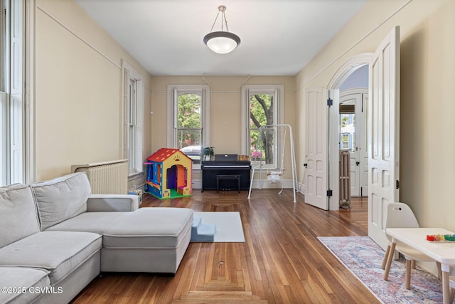 living room featuring radiator, wood finished floors, and arched walkways