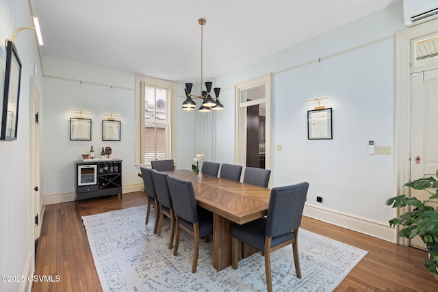 dining room with a chandelier, an AC wall unit, dark wood-type flooring, and baseboards