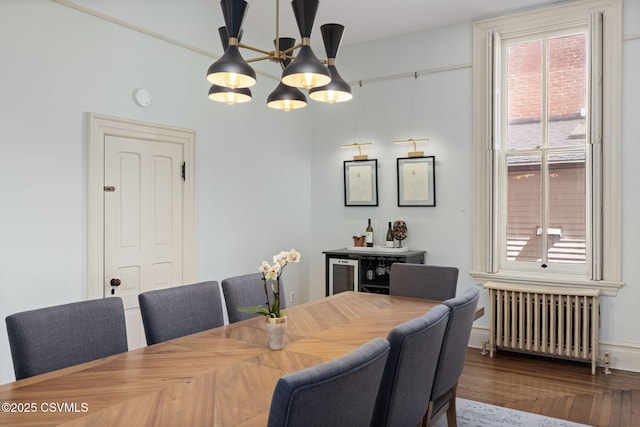 dining space with radiator, a chandelier, and wood finished floors
