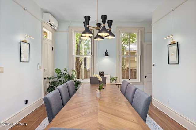 dining space with a chandelier, a wall mounted air conditioner, wood finished floors, and baseboards
