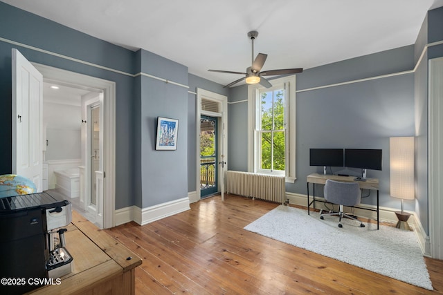 office area featuring radiator, ceiling fan, hardwood / wood-style floors, and baseboards