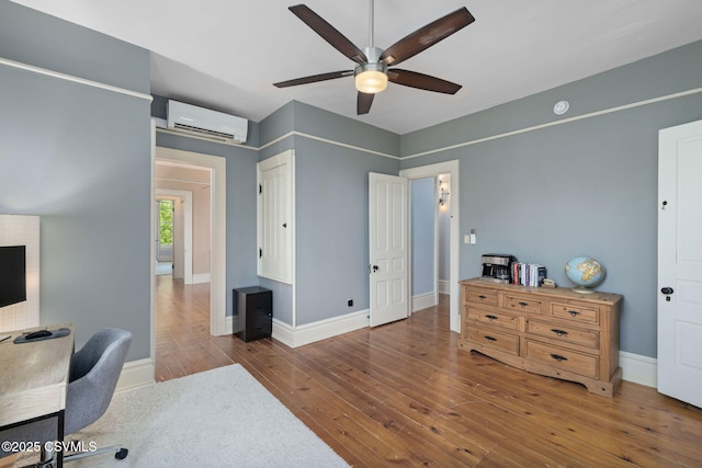 office with a wall unit AC, ceiling fan, hardwood / wood-style floors, and baseboards