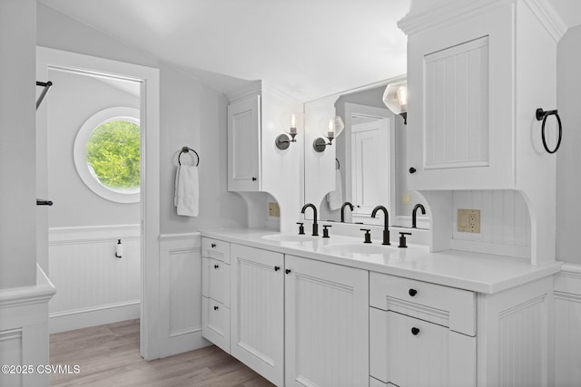 bathroom featuring wood finished floors, a wainscoted wall, and vanity
