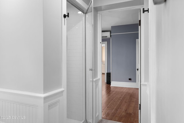 corridor featuring wood-type flooring and an AC wall unit