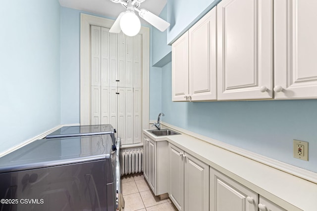 clothes washing area with radiator heating unit, washing machine and clothes dryer, cabinet space, a ceiling fan, and light tile patterned floors