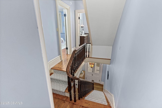 staircase featuring wood finished floors and baseboards