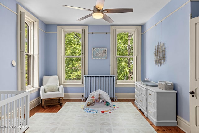 bedroom featuring radiator heating unit, multiple windows, and wood finished floors