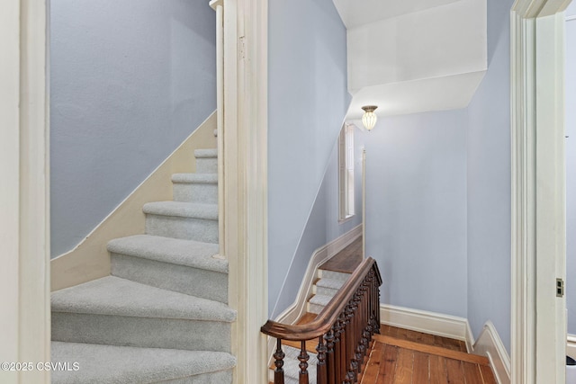 staircase featuring wood finished floors and baseboards