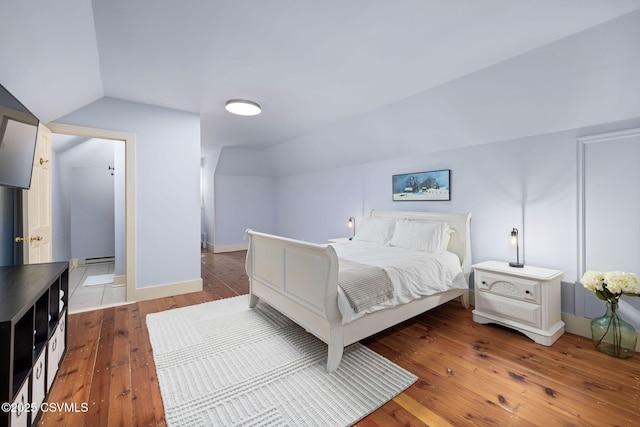 bedroom featuring vaulted ceiling, hardwood / wood-style flooring, and baseboard heating