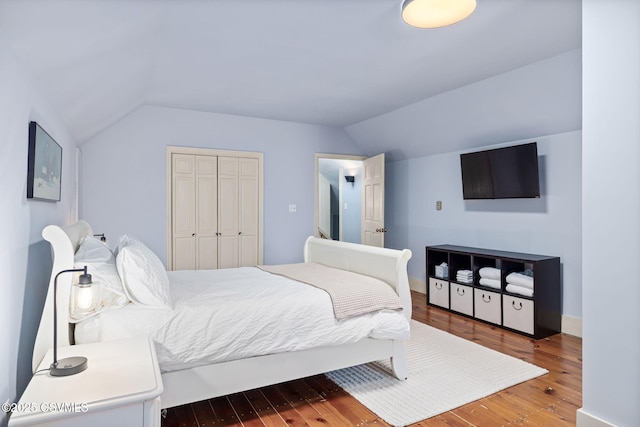 bedroom with lofted ceiling, wood finished floors, and a closet