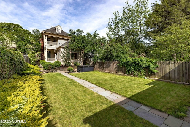 view of yard featuring a balcony and a hot tub