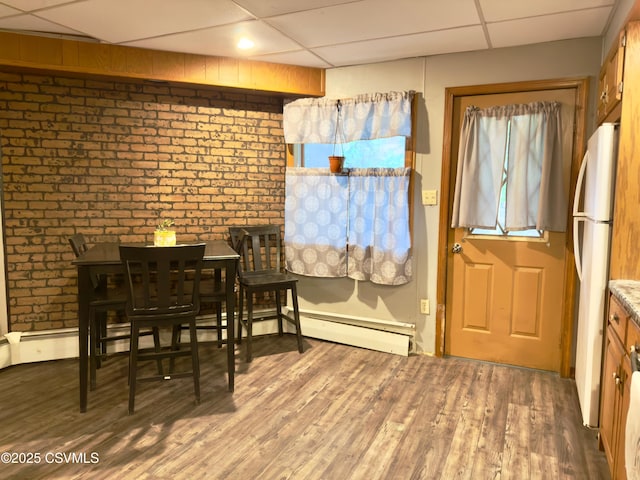 303 Melrose St, Marion Heights, PA 17832 - dining area featuring a paneled ceiling, a baseboard heating unit, healthy amount of natural light, wood finished floors, and brick wall