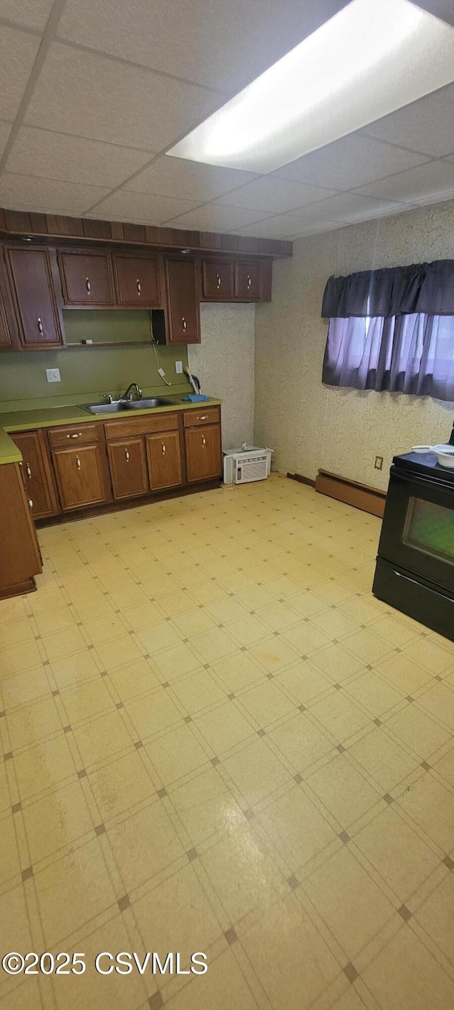 kitchen with a sink, a paneled ceiling, light floors, and light countertops