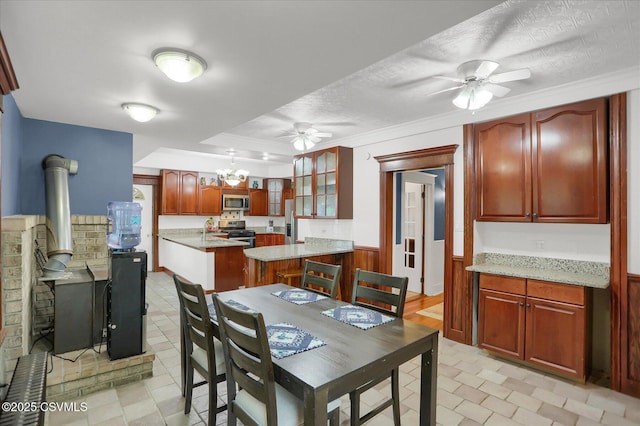 288 Broadway St, Turbotville, PA 17772 - dining space with a ceiling fan, a wood stove, a chandelier, a wainscoted wall, and a textured ceiling