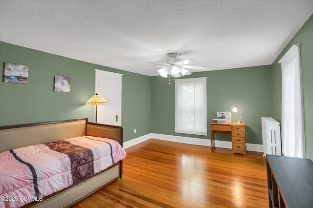 288 Broadway St, Turbotville, PA 17772 - bedroom featuring radiator heating unit, a textured ceiling, wood-type flooring, baseboards, and ceiling fan