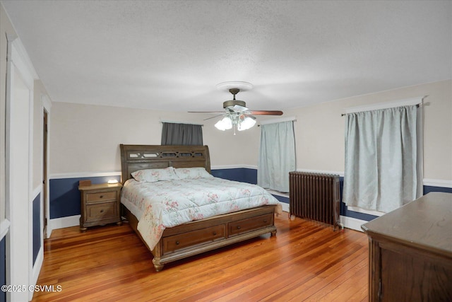 288 Broadway St, Turbotville, PA 17772 - bedroom featuring radiator heating unit, light wood-style flooring, a ceiling fan, and a textured ceiling
