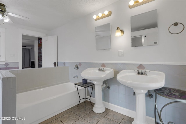 288 Broadway St, Turbotville, PA 17772 - bathroom featuring a bath, tile walls, tile patterned floors, a textured ceiling, and wainscoting