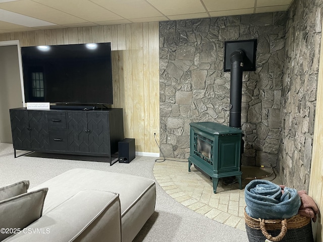 3014 Smoketown Rd, Lewisburg, PA 17837 - living room featuring carpet flooring, a wood stove, a drop ceiling, wooden walls, and baseboards