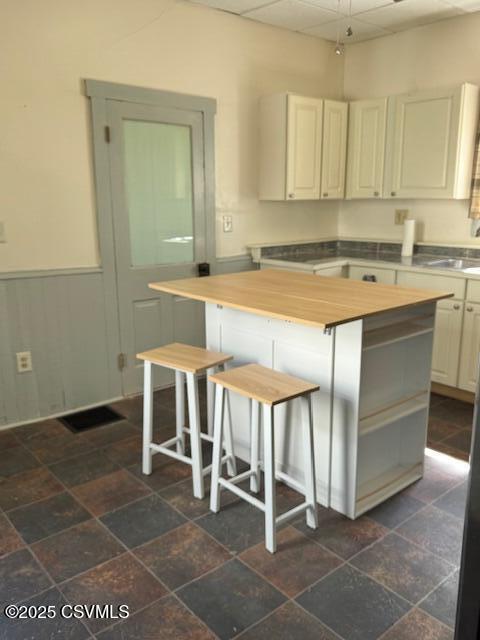 833 Line St, Sunbury, PA 17801 - kitchen with butcher block counters, a sink, a kitchen island, stone tile flooring, and a kitchen breakfast bar