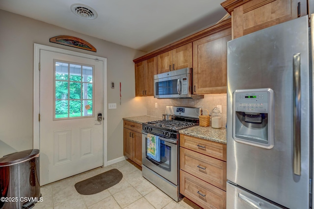475 W 1st St, Bloomsburg, PA 17815 - kitchen with appliances with stainless steel finishes, light stone counters, backsplash, brown cabinets, and baseboards