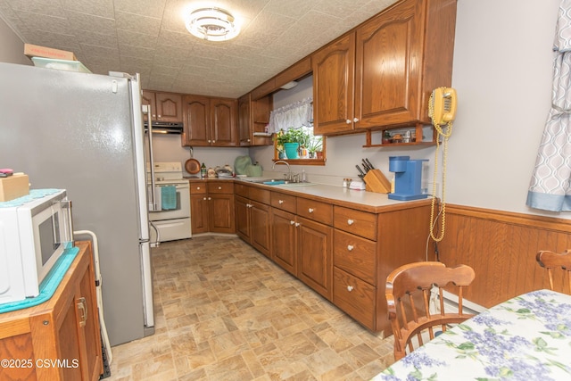 2256 Crossroads Dr, Lewisburg, PA 17837 - kitchen featuring white appliances, a sink, brown cabinetry, a wainscoted wall, and wood walls