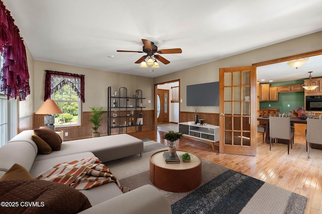 620 Sunset Dr, Bloomsburg, PA 17815 - living room featuring a wainscoted wall, light wood finished floors, a ceiling fan, french doors, and wooden walls
