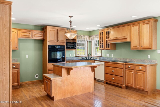 620 Sunset Dr, Bloomsburg, PA 17815 - kitchen with black appliances, glass insert cabinets, light wood-type flooring, a center island, and a breakfast bar area