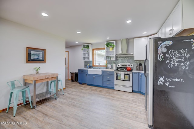 67 Center School Rd, Elysburg, PA 17824 - kitchen with stainless steel appliances, wall chimney exhaust hood, blue cabinetry, white cabinets, and light wood-style floors