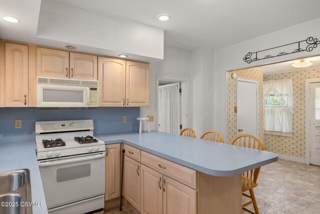 651 E Market St, Danville, PA 17821 - kitchen featuring white appliances, light brown cabinets, a peninsula, a breakfast bar, and wallpapered walls