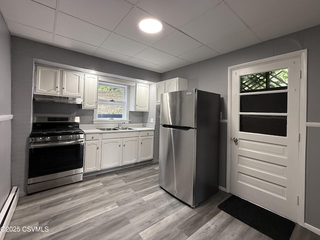 423 E Dewart St, Shamokin, PA 17872 - kitchen with appliances with stainless steel finishes, a baseboard radiator, under cabinet range hood, white cabinetry, and light countertops