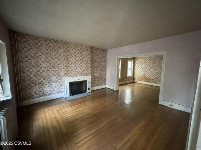 127 N 3rd St, Lewisburg, PA 17837 - unfurnished living room featuring wallpapered walls, baseboards, a fireplace, parquet floors, and radiator