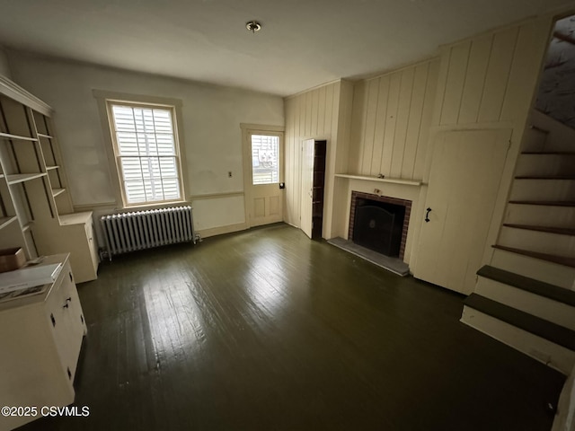 127 N 3rd St, Lewisburg, PA 17837 - unfurnished living room with radiator, stairs, a brick fireplace, and dark wood finished floors