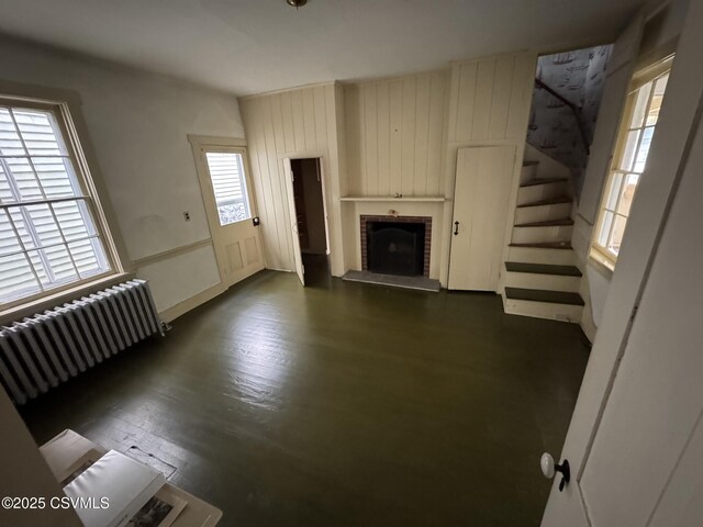 127 N 3rd St, Lewisburg, PA 17837 - unfurnished living room with radiator heating unit, a brick fireplace, stairway, and dark wood finished floors