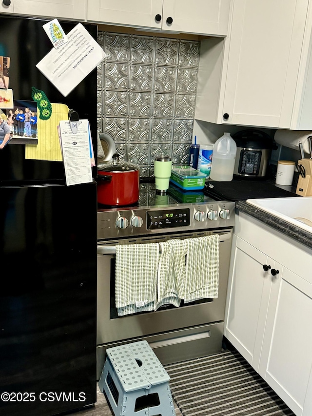511 Snowflake Ln, Shickshinny, PA 18655 - kitchen with freestanding refrigerator, stainless steel electric stove, white cabinets, and tasteful backsplash
