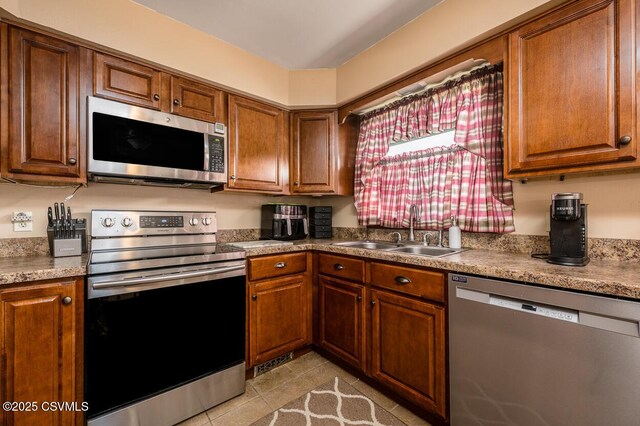 306 Clybourne Ave, Berwick, PA 18603 - kitchen with stainless steel appliances, a sink, light tile patterned floors, and brown cabinets