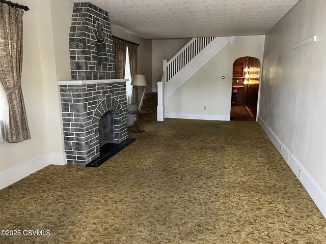 1409 Scott St, Kulpmont, PA 17834 - unfurnished living room featuring carpet floors, arched walkways, stairway, and a tile fireplace