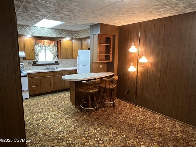 1409 Scott St, Kulpmont, PA 17834 - kitchen featuring white appliances, a sink, wooden walls, range hood, and a peninsula