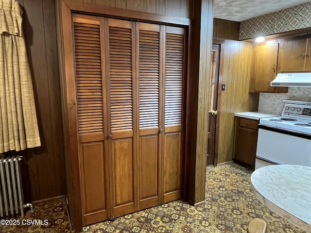 1409 Scott St, Kulpmont, PA 17834 - kitchen featuring electric range, under cabinet range hood, radiator heating unit, light countertops, and wood walls