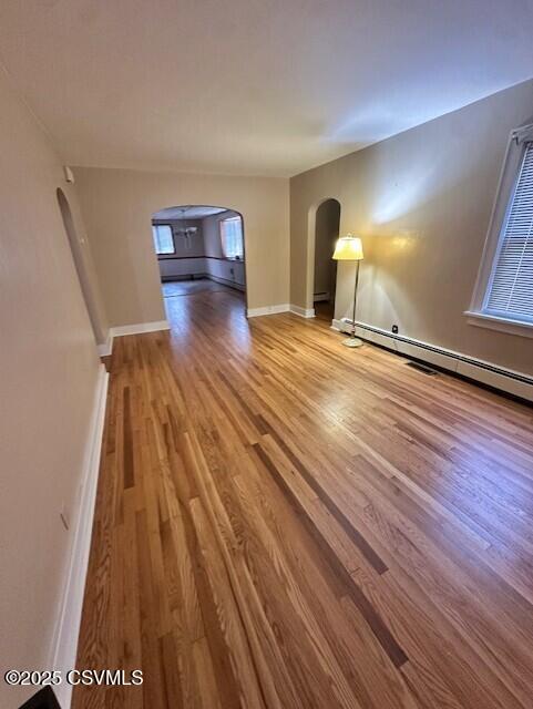 1030 Orange St, Berwick, PA 18603 - unfurnished living room featuring arched walkways, wood finished floors, and baseboard heating