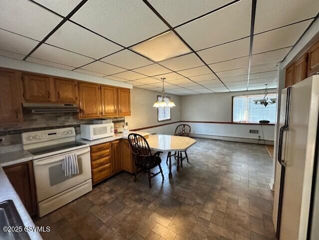 1030 Orange St, Berwick, PA 18603 - kitchen featuring white appliances, a chandelier, a drop ceiling, brown cabinets, and under cabinet range hood