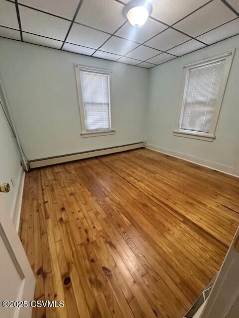 1030 Orange St, Berwick, PA 18603 - unfurnished room featuring baseboard heating, a drop ceiling, and hardwood / wood-style flooring