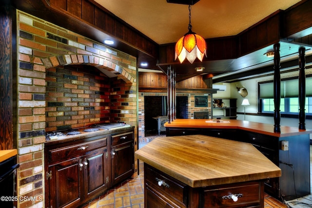 157 Distillery Hill Rd, Benton, PA 17814 - kitchen with butcher block countertops, a center island, decorative light fixtures, dark brown cabinetry, and brick wall