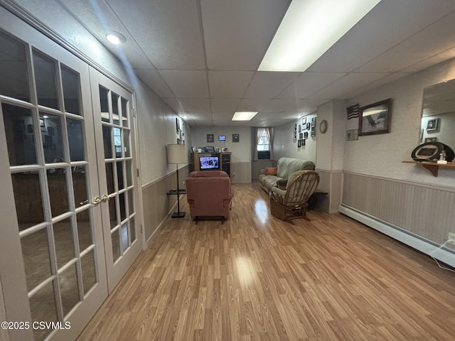 1211 W Mulberry St, Coal Township, PA 17866 - living area featuring wood finished floors, a drop ceiling, french doors, a wainscoted wall, and a baseboard radiator