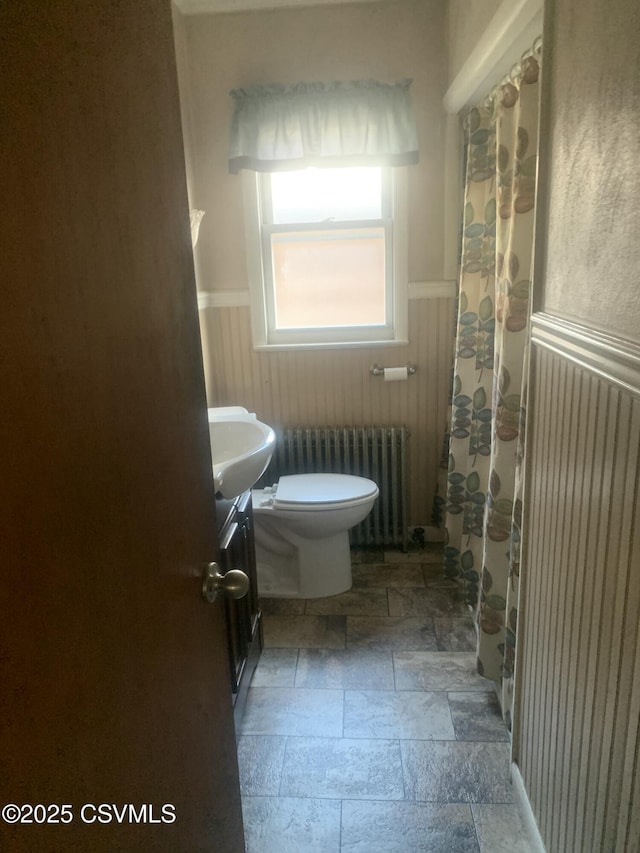 1542 1st Ave, Berwick, PA 18603 - bathroom featuring radiator heating unit, wainscoting, stone tile flooring, vanity, and a shower with curtain
