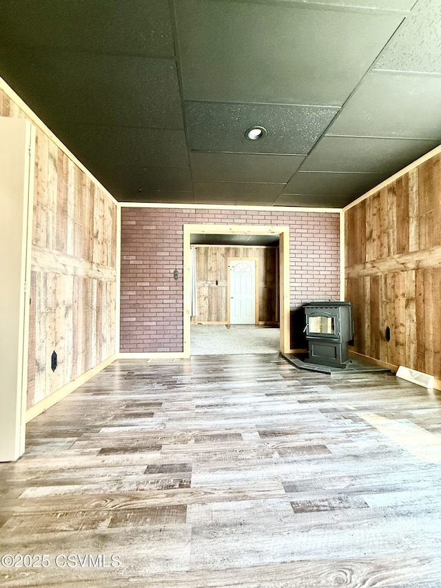 333 E Bowman St, Berwick, PA 18603 - unfurnished living room featuring a wood stove, wood walls, a drop ceiling, and wood finished floors