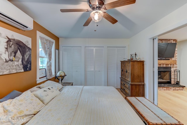 909 Fair St, Nescopeck, PA 18635 - bedroom featuring a wall mounted air conditioner, multiple closets, a brick fireplace, wood finished floors, and ceiling fan