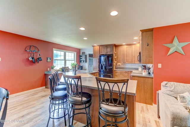 909 Fair St, Nescopeck, PA 18635 - kitchen featuring black fridge, light wood finished floors, recessed lighting, a kitchen breakfast bar, and a kitchen island with sink